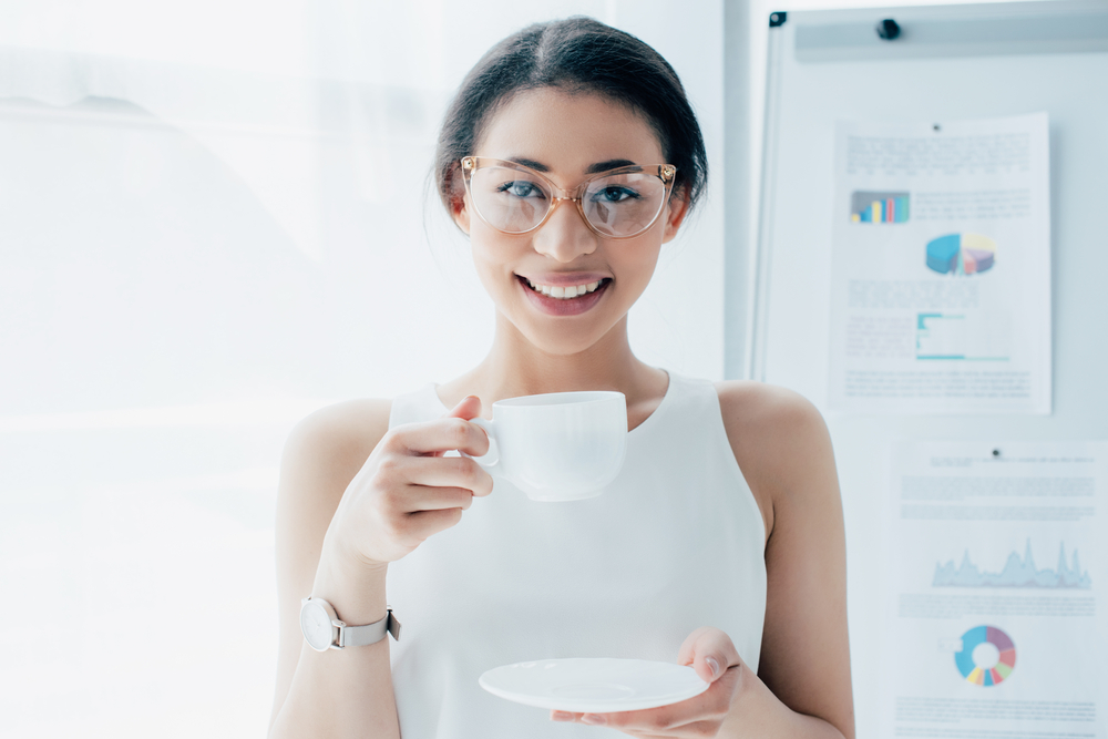 Young female entrepreneur with coffee cup in front of business plan board with value drivers